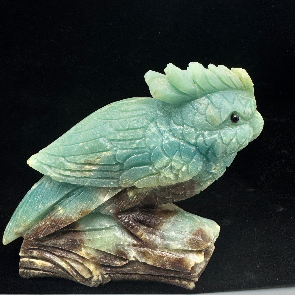 A side profile of the Amazonite parrot sculpture, highlighting the intricate details of its wings and tail feathers.