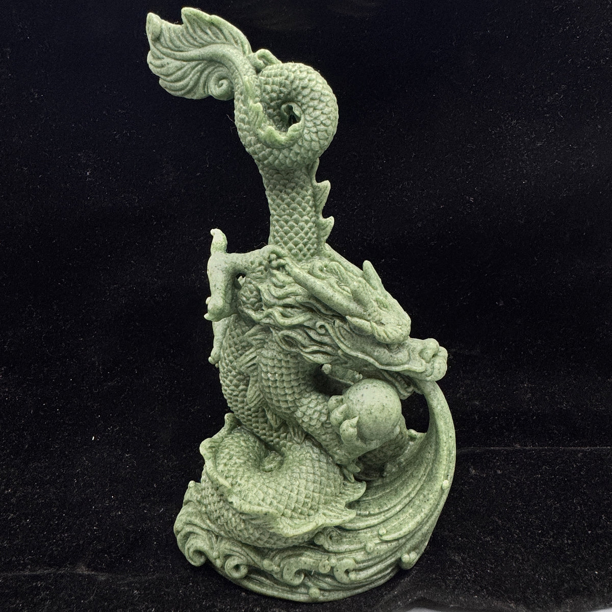 The bluestone dragon figurine sitting majestically on a rock crystal base.