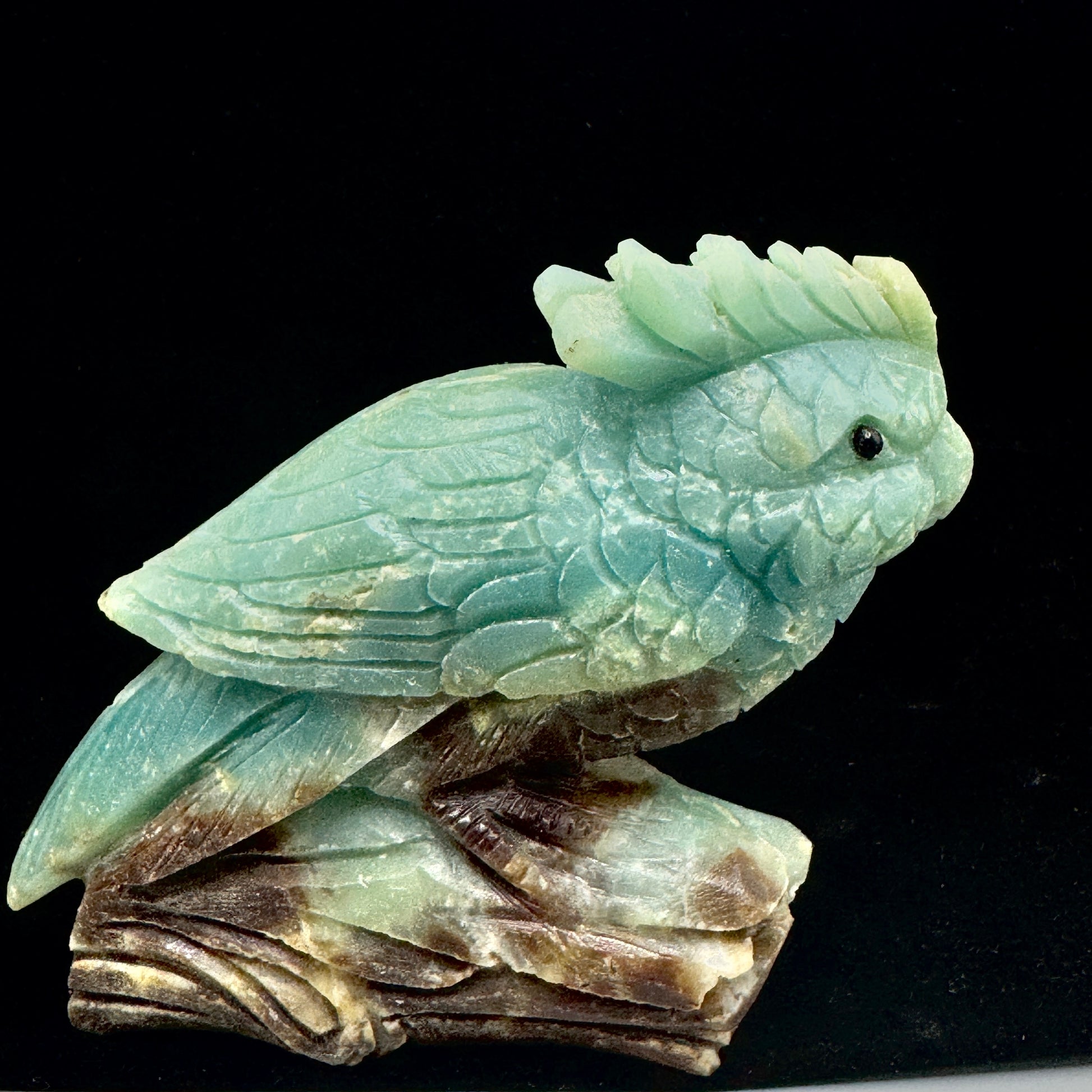 The front view of the exquisite hand-carved Amazonite parrot, showcasing its vibrant blue-green color and graceful posture.