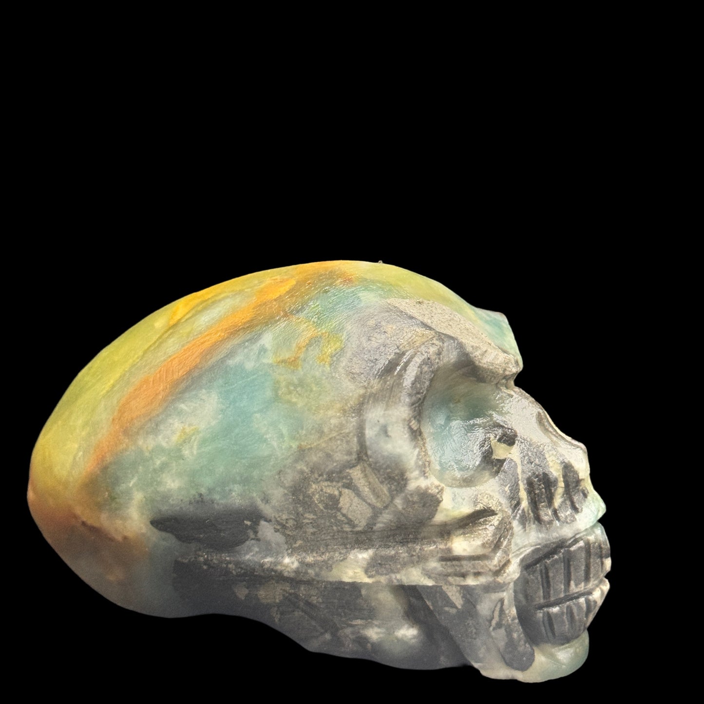 A hand-carved amazonite crystal skull on a dark background.