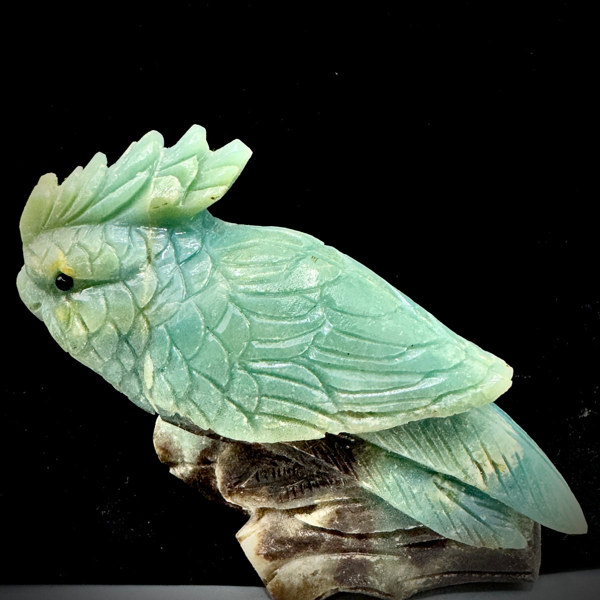 A front-facing view of the exquisite hand-carved Amazonite parrot, showcasing its vibrant blue-green color and lifelike posture.