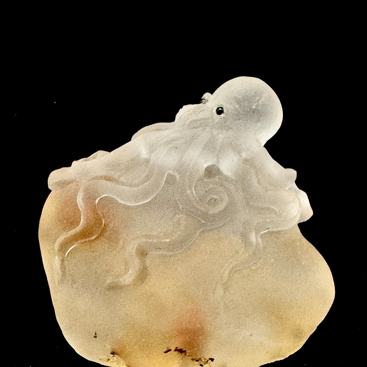 A clear crystal octopus hand-carved with intricate details, placed on a wooden stand for spiritual decor.