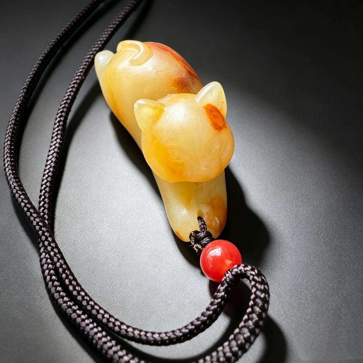 Natural jade carved resting cat pendant necklace with black cord and red bead
