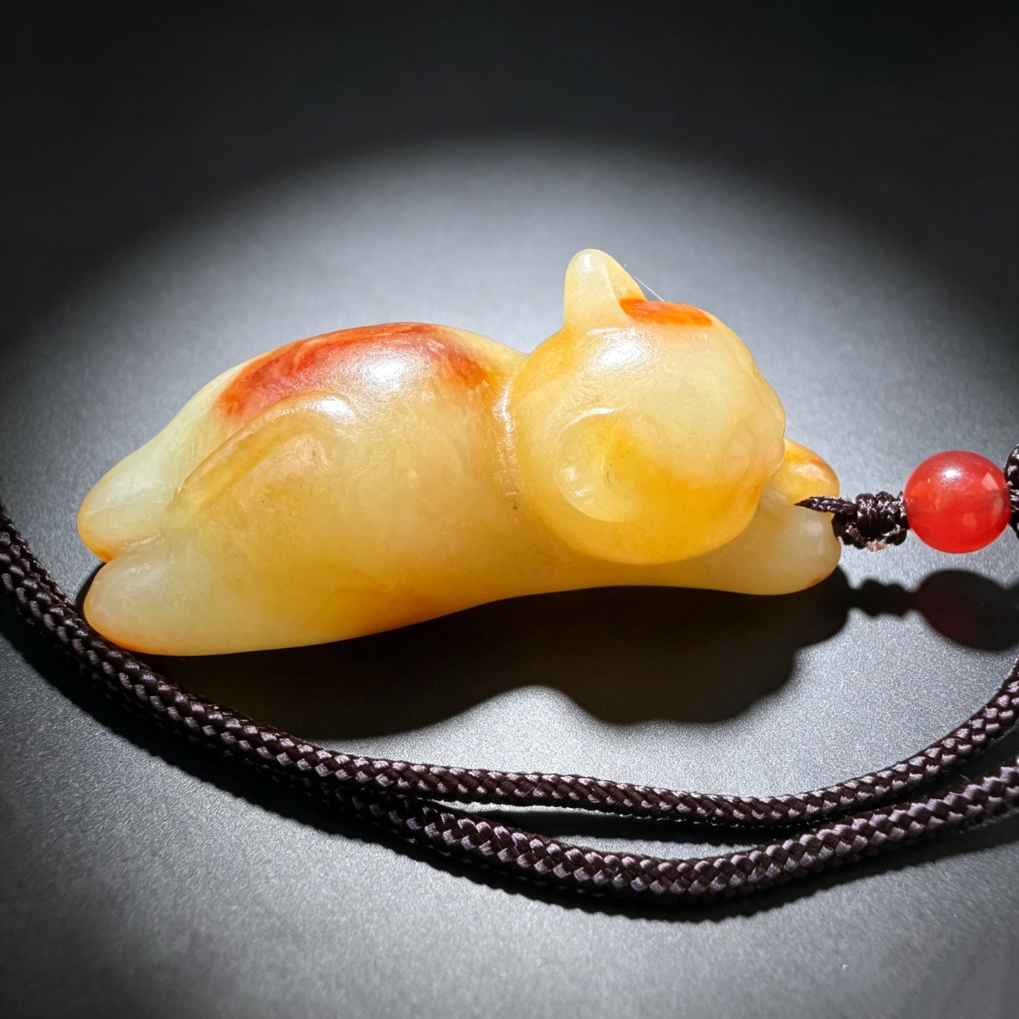 Natural jade cat pendant top view showing orange and golden stone variations