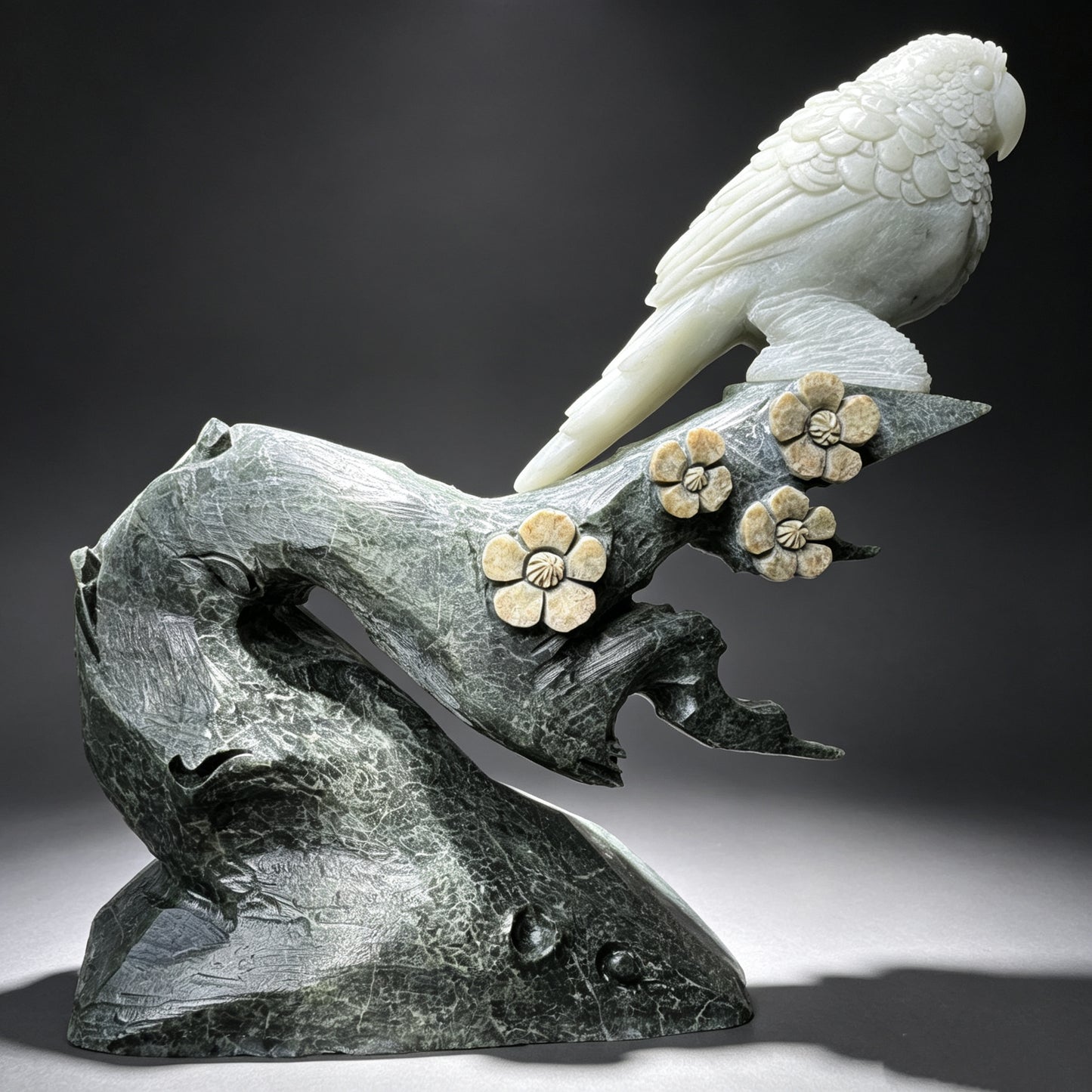 Natural stone hand carved parrot sculpture on floral stone branch, full side profile.
