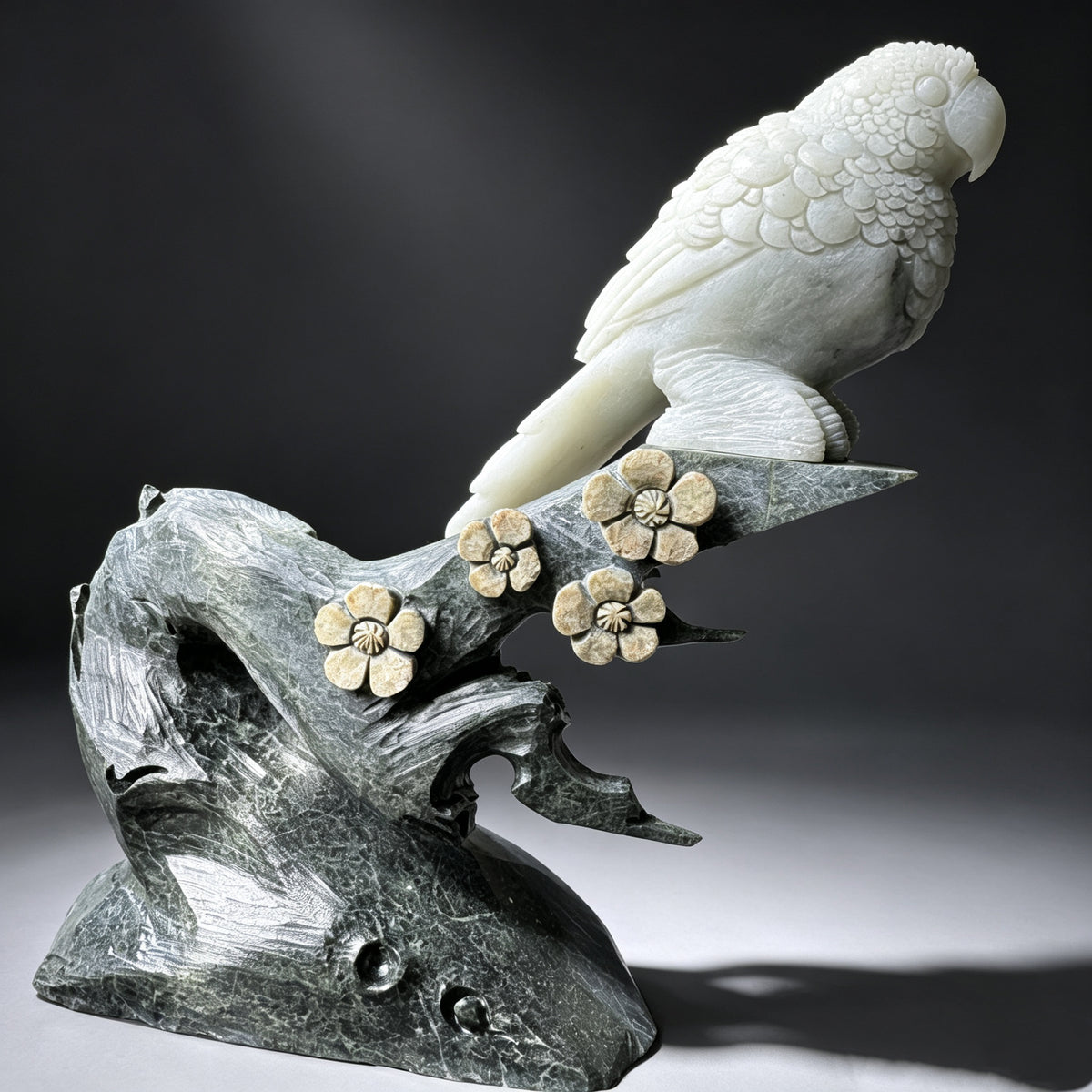 Natural stone hand carved parrot sculpture with detailed feathers, stone branch and carved flower accents.