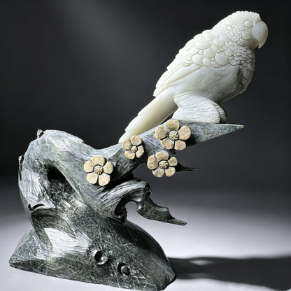 Natural stone hand carved parrot sculpture with detailed feathers, stone branch and carved flower accents.