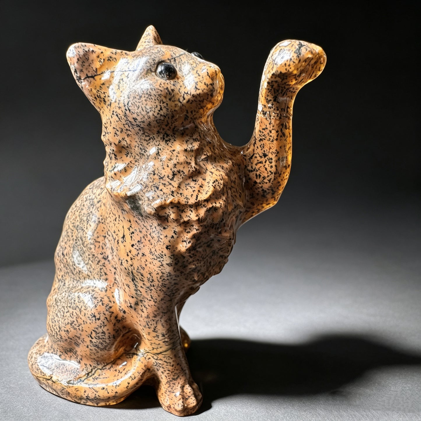 Carved natural stone cat figurine side view showing speckled patterns