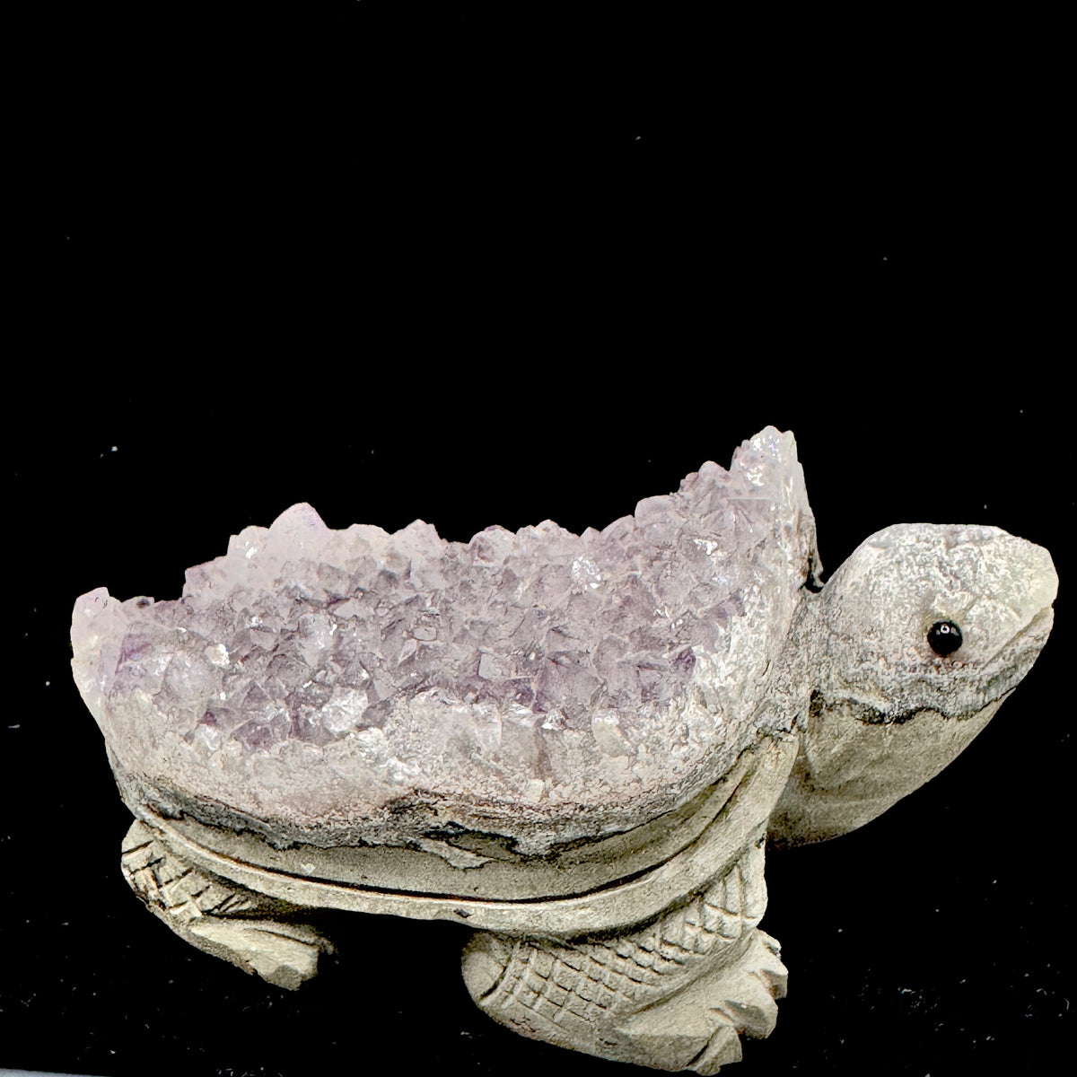 A side profile view showing the tortoise form emerging from the raw geode of the amethyst cluster.