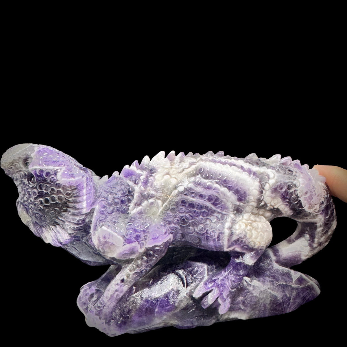 Close-up of the lizard figurine sitting on the raw amethyst crystal base.