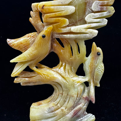 The bird and flower statue being held in two hands, suggesting a gift or personal connection.