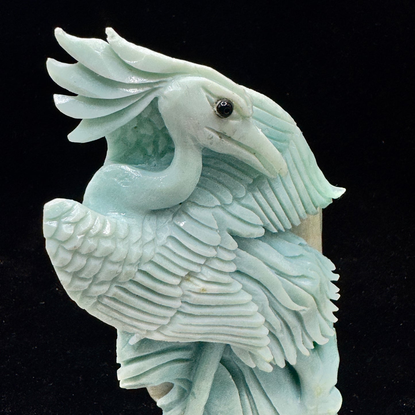 A profile view highlighting the bird's carved details and the stone's natural marbling.