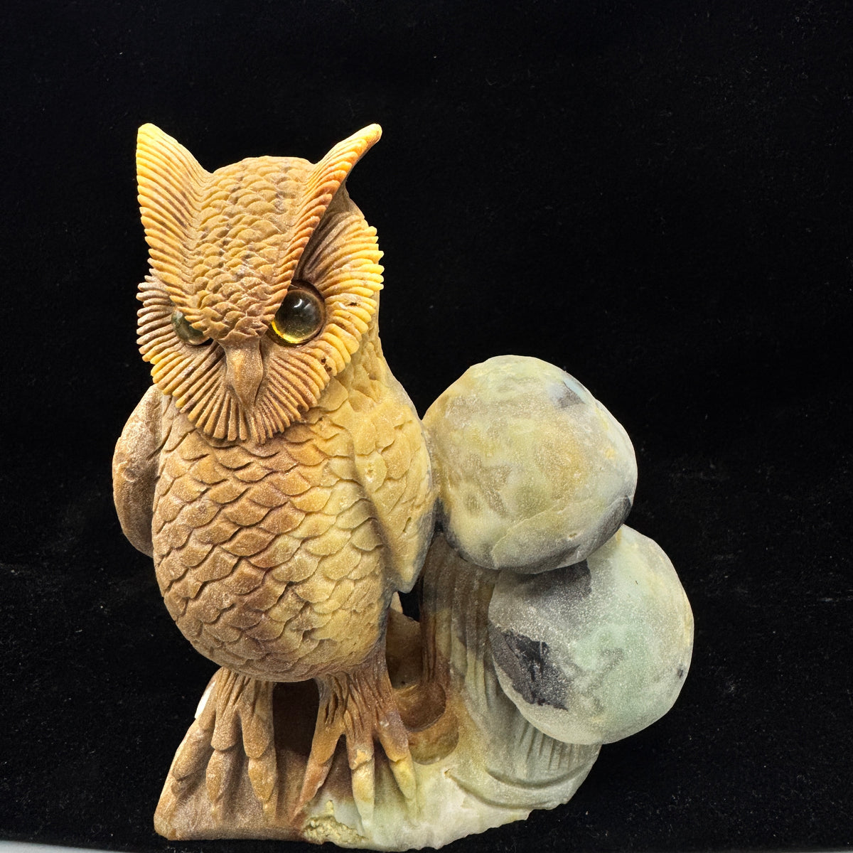 A detailed side view showing the owl's carved features and the stone's natural patterns.