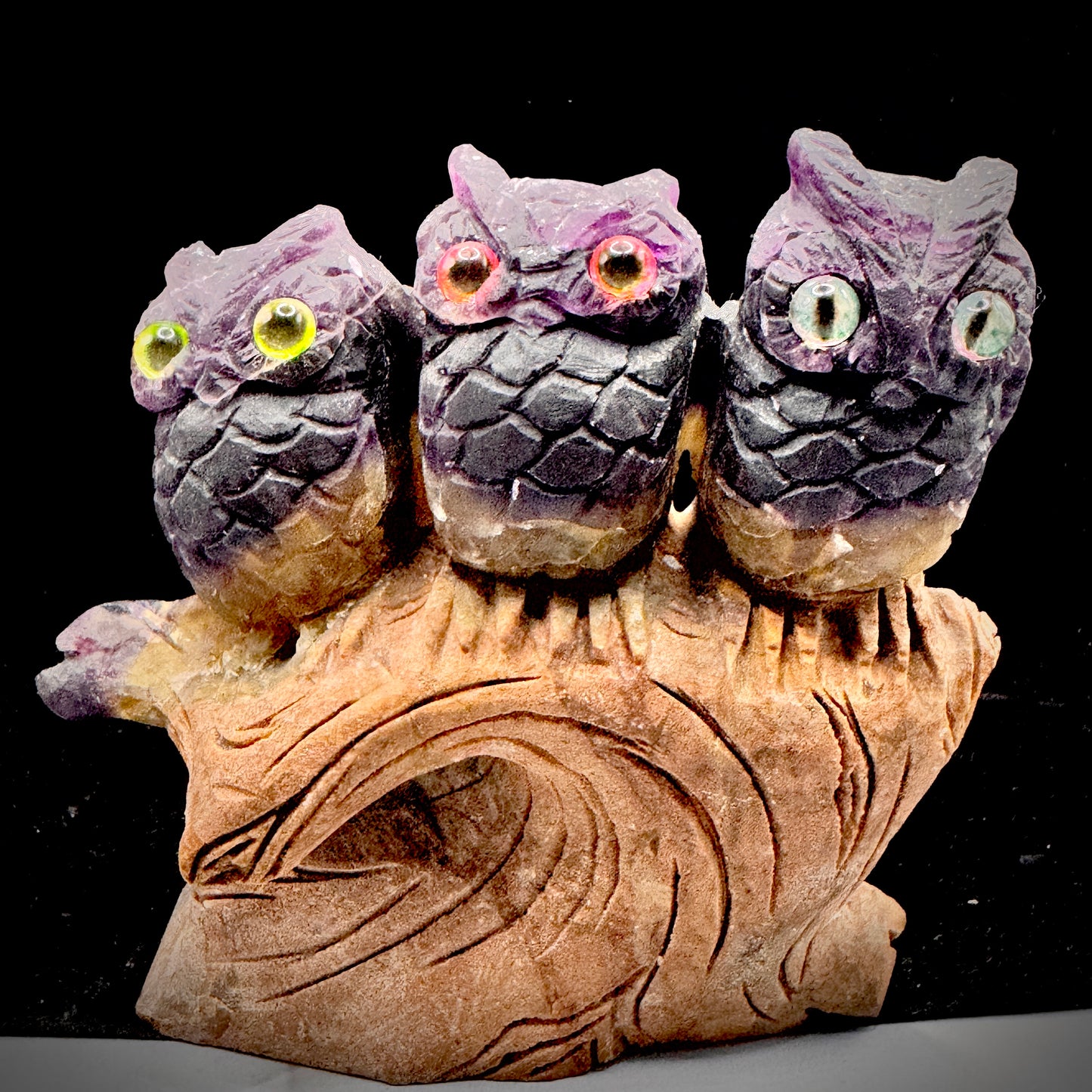 Rainbow fluorite owl trio as decision making symbol on bookshelf