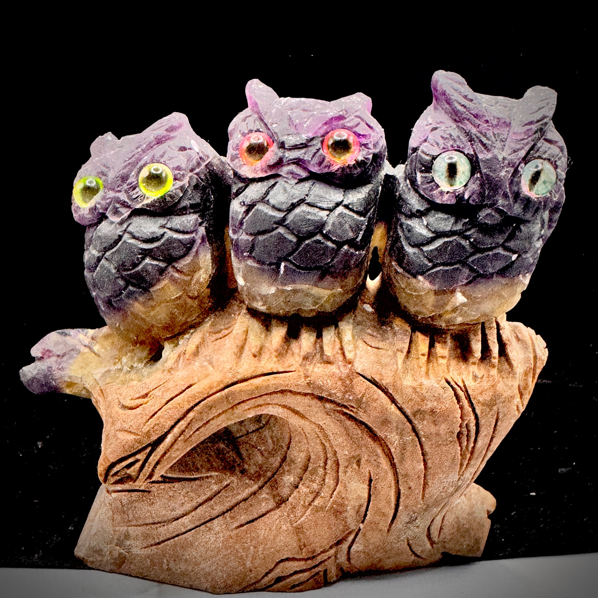 Rainbow fluorite owl trio as decision making symbol on bookshelf