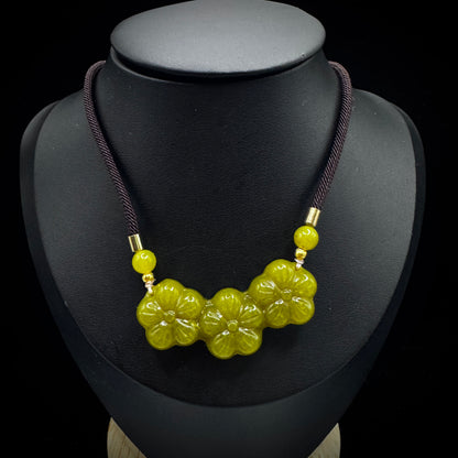 Close-up of a golden serpentine stone pendant, showcasing natural stone patterns and hand-carved craftsmanship.