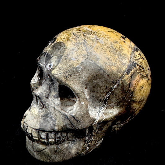 Close-up of a skull ornament carved from natural minerals, showcasing unique mineral textures and hand-polished finish.