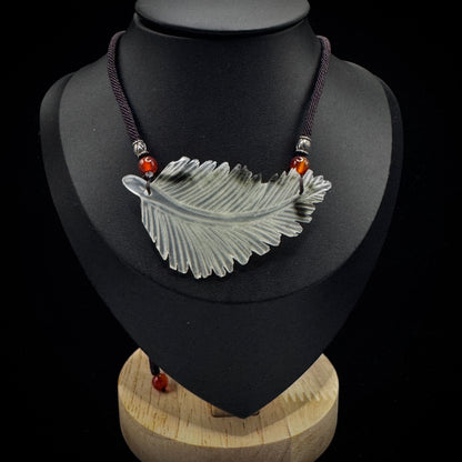 Side view of earth energy feather pendant showing carving details