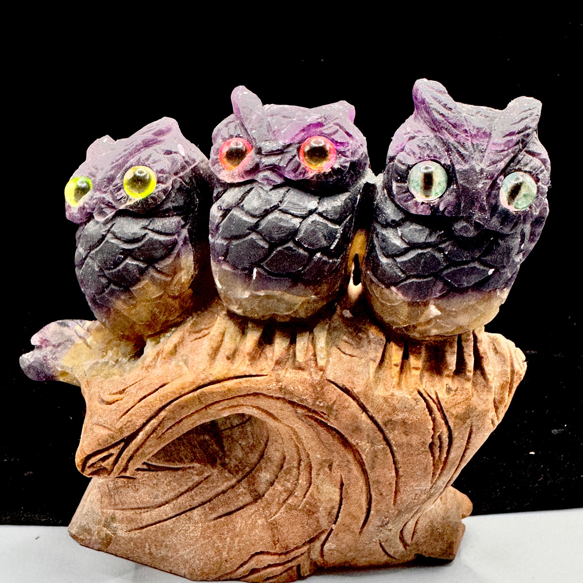 Rainbow fluorite owls showing natural purple and green color zoning in sunlight