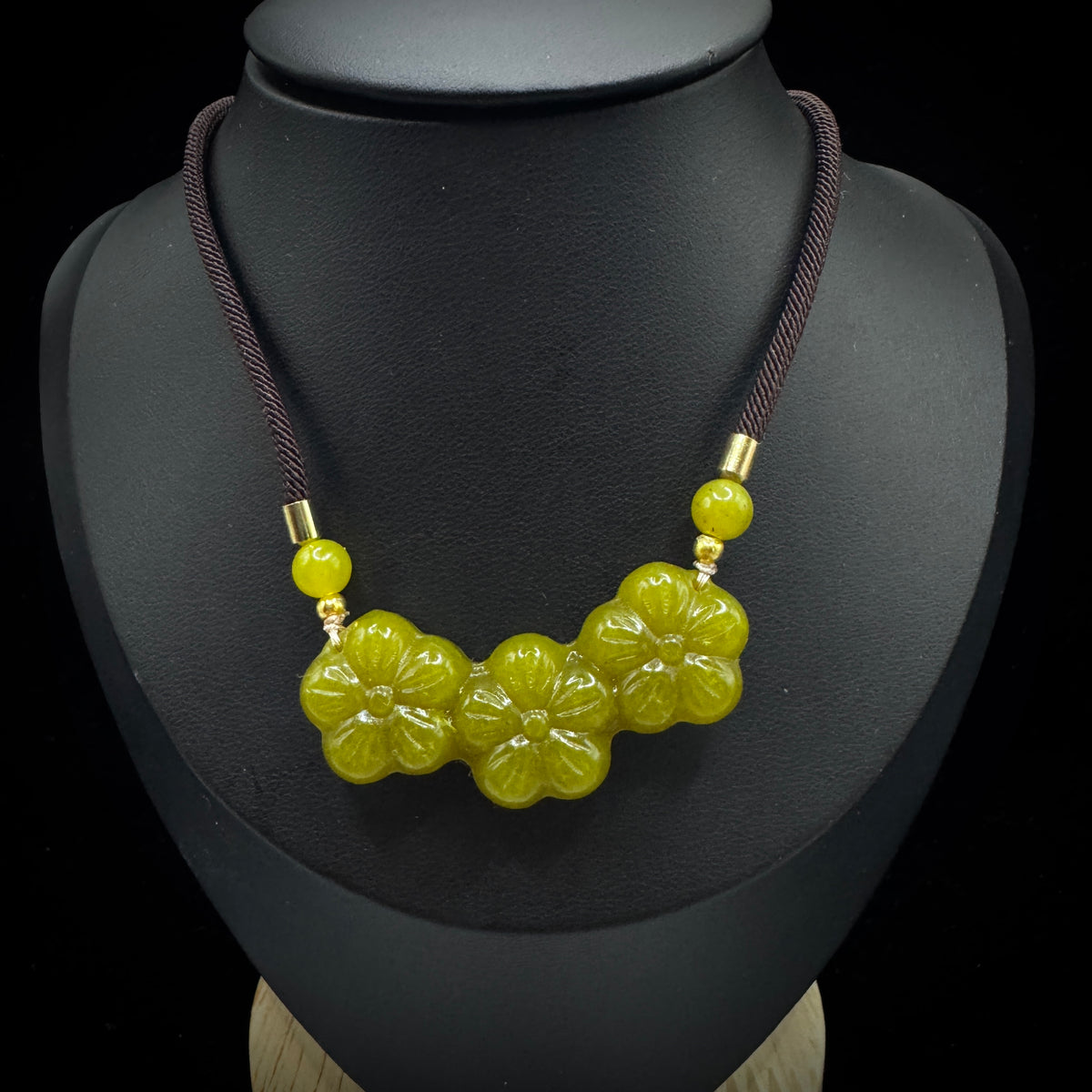 Front view display of a yellow serpentine stone flower pendant, showcasing exquisite floral carving details.